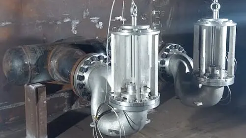 Two stainless steel valve assemblies are mounted on large industrial piping inside a metal-lined chamber.