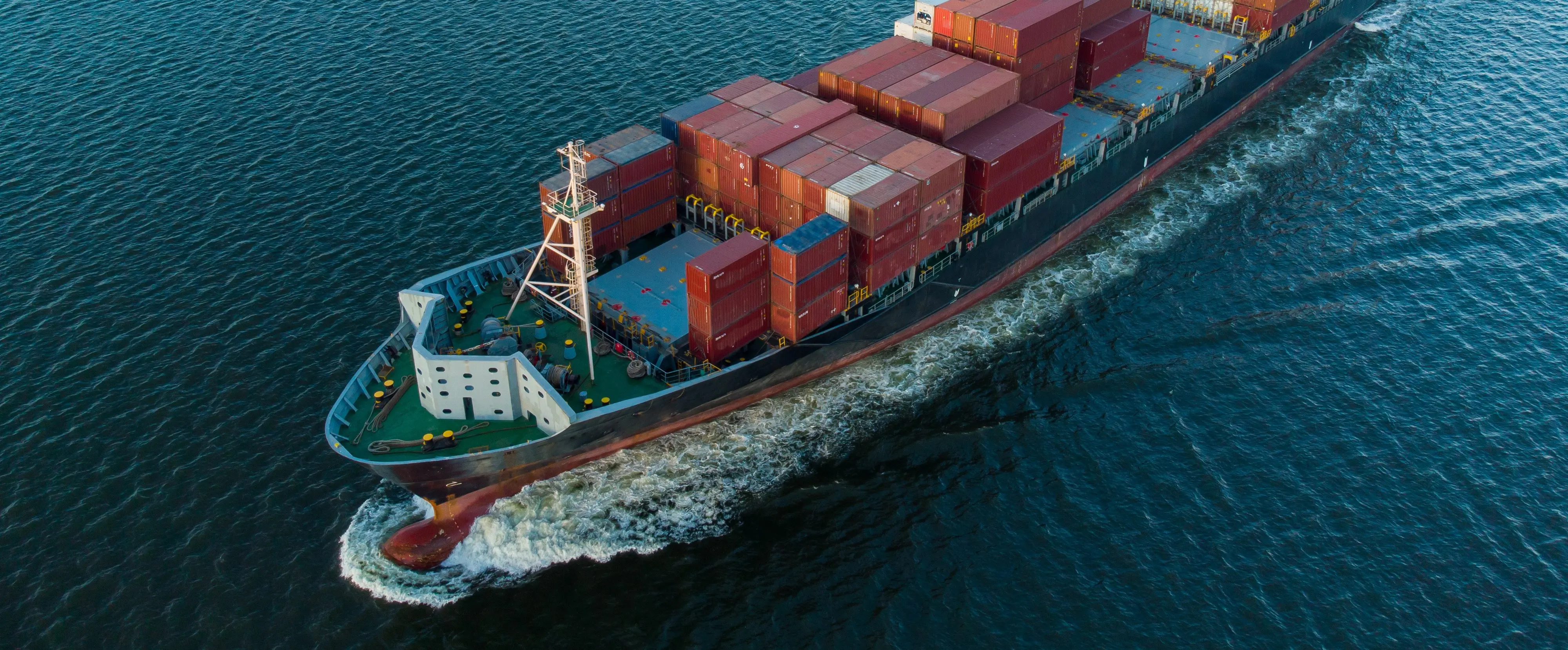 A cargo ship loaded with containers sailing through the ocean, representing marine and offshore industries
